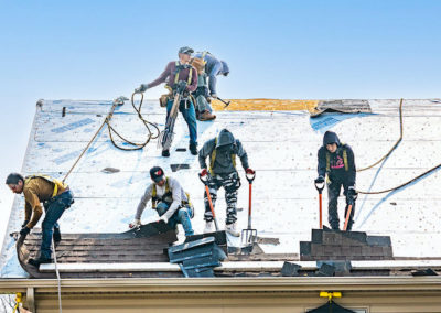 team of roofers removing old shingles from roof in McHenry